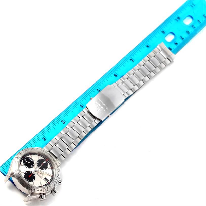 The Omega Speedmaster 3211.31.00 Men
s Stainless Steel Silver Dial 3211.31.00 Men
s Stainless Steel Silver Dial watch is shown from a top-down angle, displaying its face, bezel, bracelet, and clasp alongside a blue ruler.