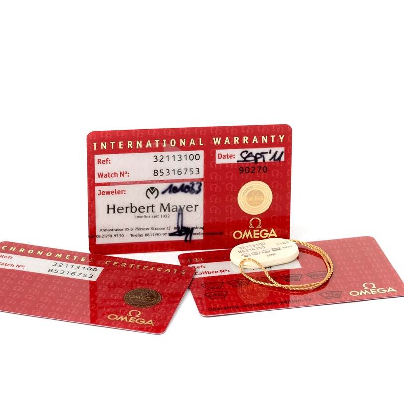 The image shows Omega Speedmaster 3211.31.00 Men
s Stainless Steel Silver Dial 3211.31.00 Men
s Stainless Steel Silver Dial
s international warranty cards and chronometer certificate at a top-angle view.