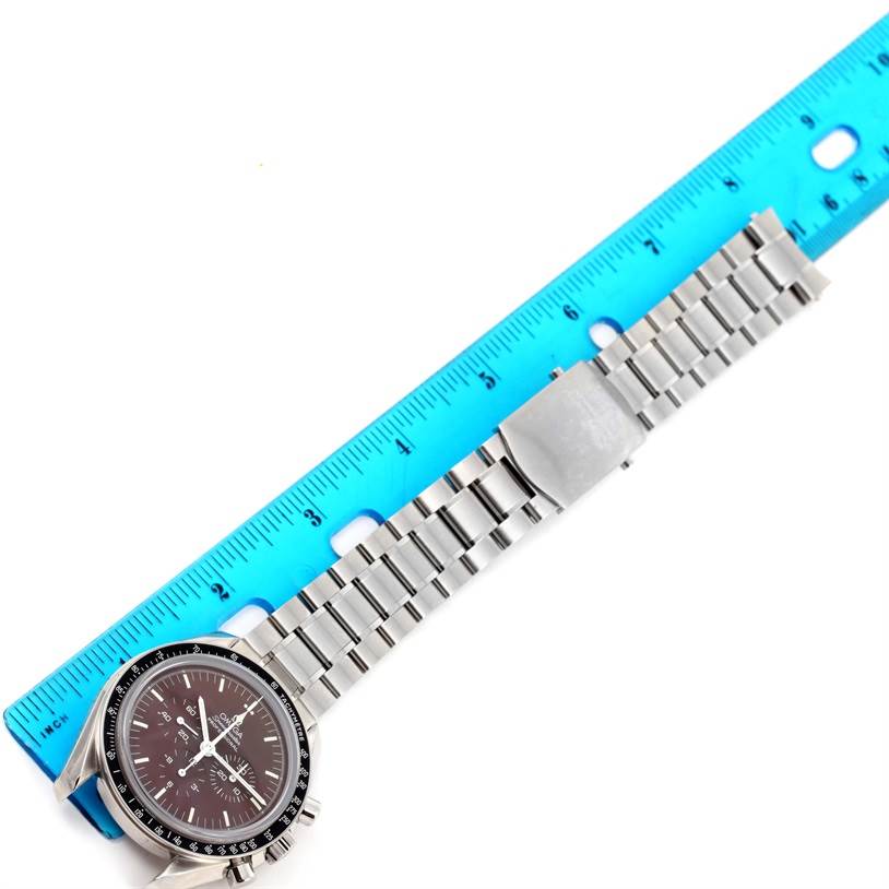 This image shows an Omega Speedmaster 311.30.42.30.13.001 Men's Stainless Steel Brown Dial 311.30.42.30.13.001 Men's Stainless Steel Brown Dial watch positioned with a blue ruler, highlighting its metal bracelet and clasp.