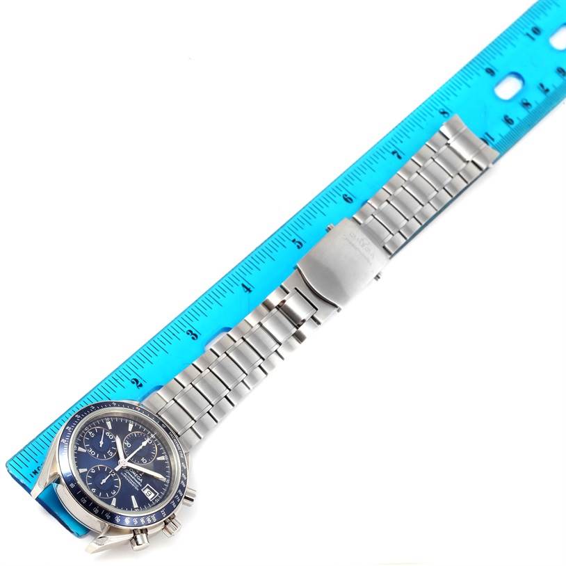 The image shows an Omega Speedmaster 3212.80.00 Men
s Stainless Steel Blue Dial 3212.80.00 Men
s Stainless Steel Blue Dial watch, featuring its face and full metal bracelet, measured next to a blue ruler.