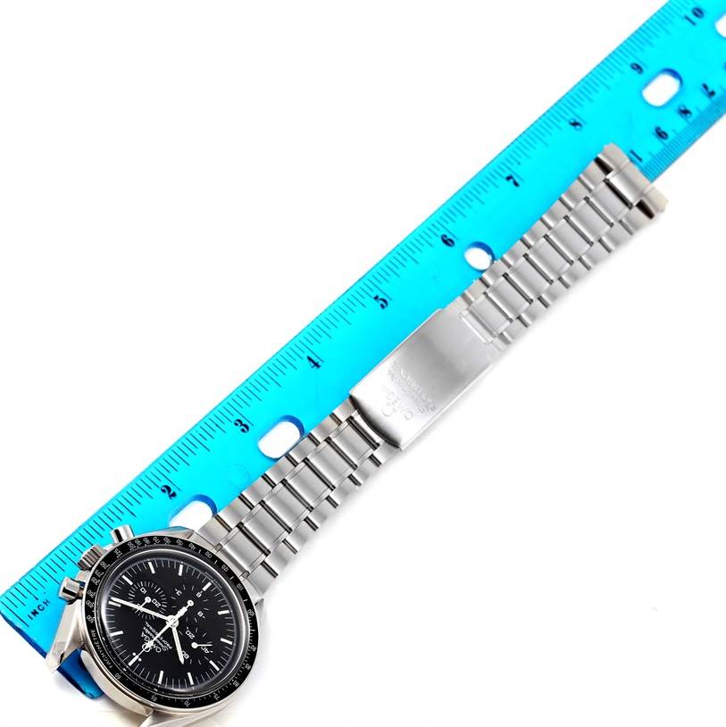 The Omega Speedmaster 3570.50.00 Men
s Stainless Steel Black Dial 3570.50.00 Men
s Stainless Steel Black Dial watch is shown laid flat with its bracelet extended alongside a blue ruler for measurement.