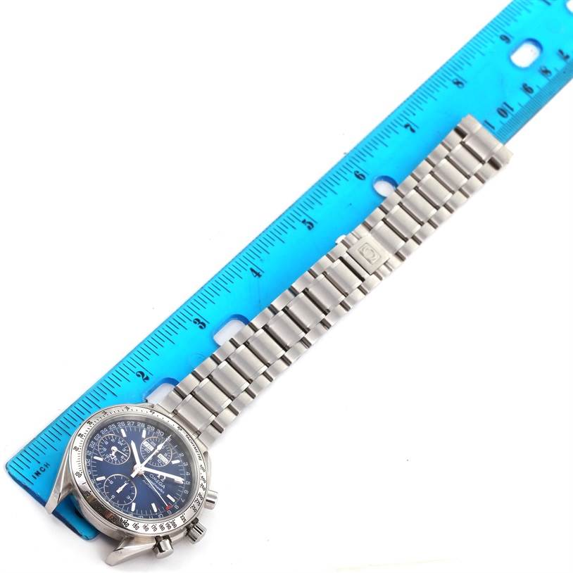 The image shows an Omega Speedmaster 3523.80.00 Men
s Stainless Steel Blue Dial 3523.80.00 Men
s Stainless Steel Blue Dial watch laid flat next to a ruler, displaying the watch face and the metal bracelet.