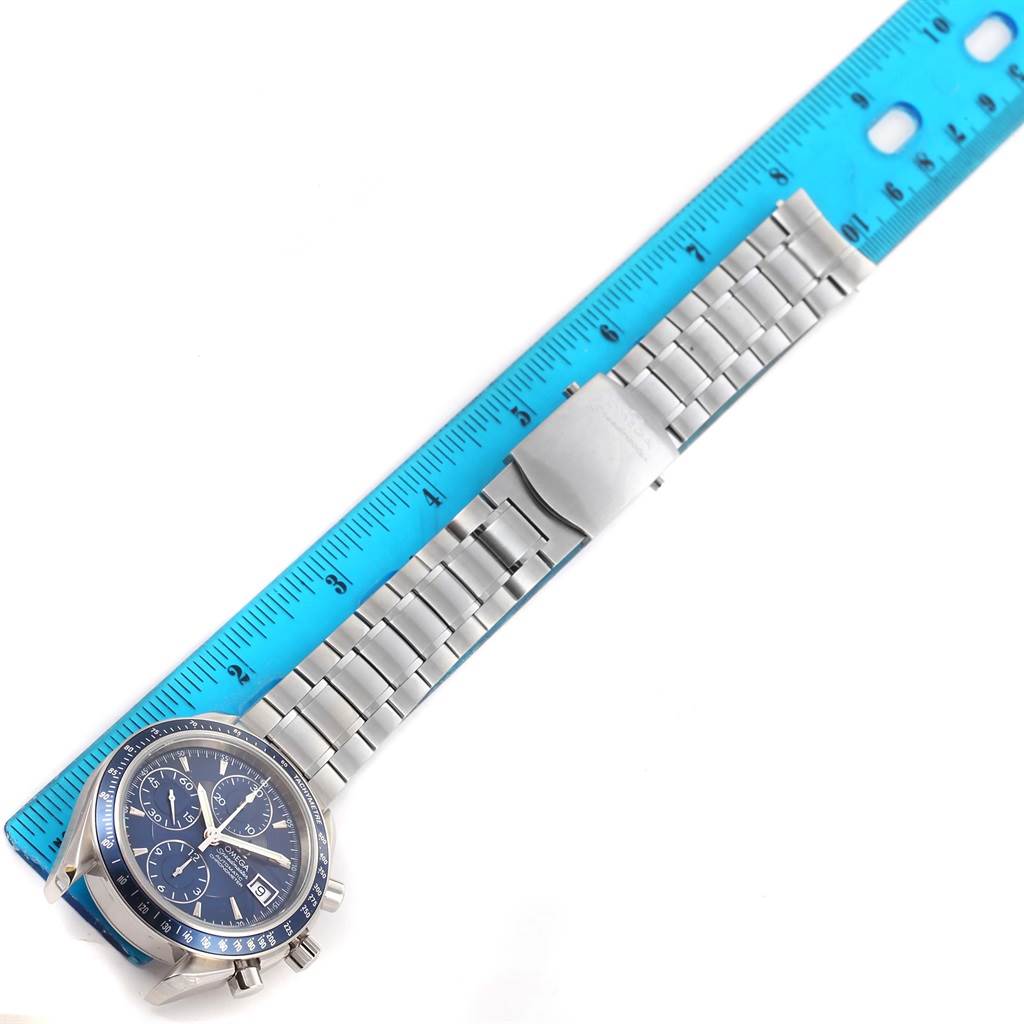 The image shows an Omega Speedmaster 3212.80.00 Men
s Stainless Steel Blue Dial 3212.80.00 Men
s Stainless Steel Blue Dial watch laid flat with a blue ruler measuring its stainless steel bracelet.