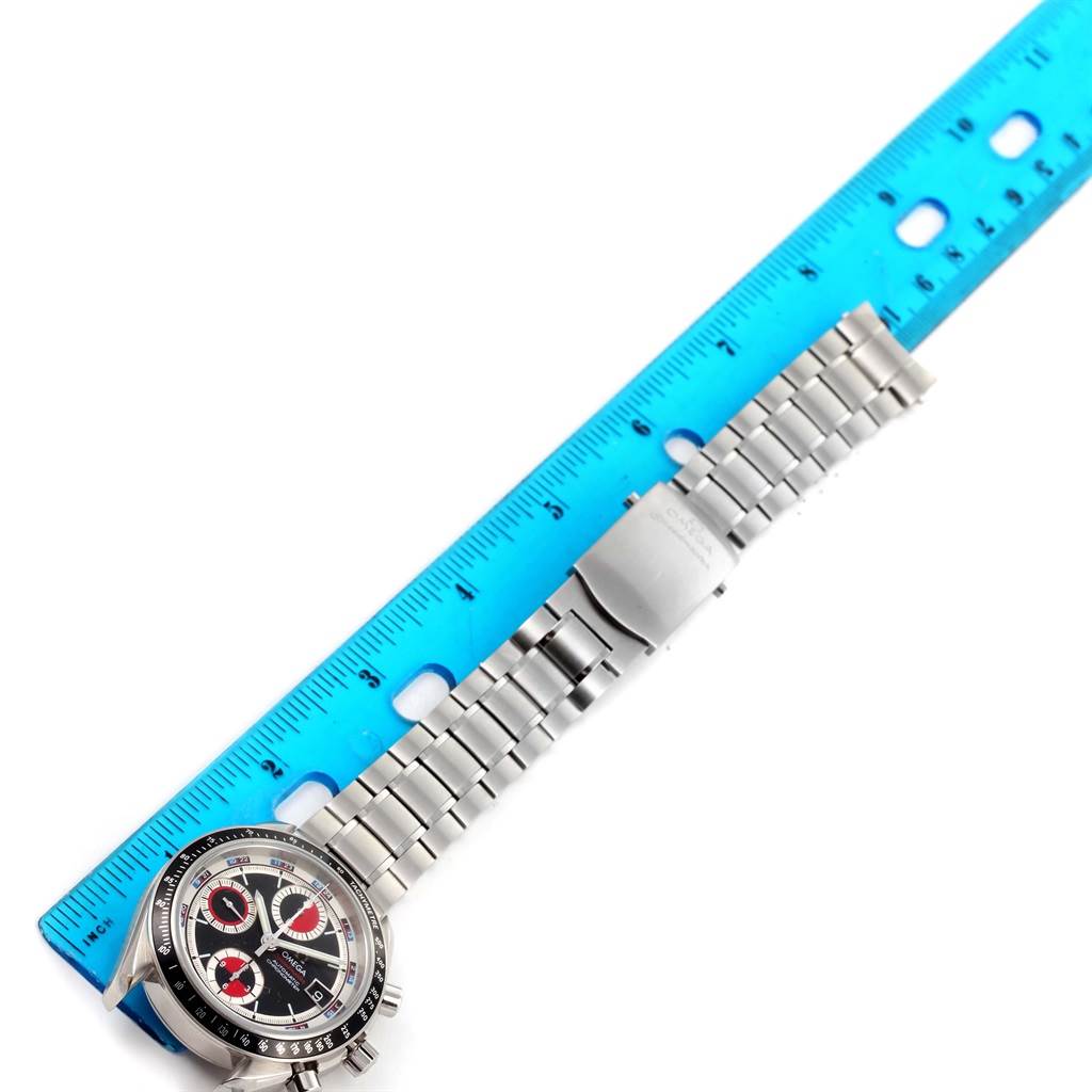 The image shows an Omega Speedmaster 3210.52.00 Men
s Stainless Steel Black Dial 3210.52.00 Men
s Stainless Steel Black Dial watch, including its face and metal bracelet, positioned alongside a blue ruler for scale.