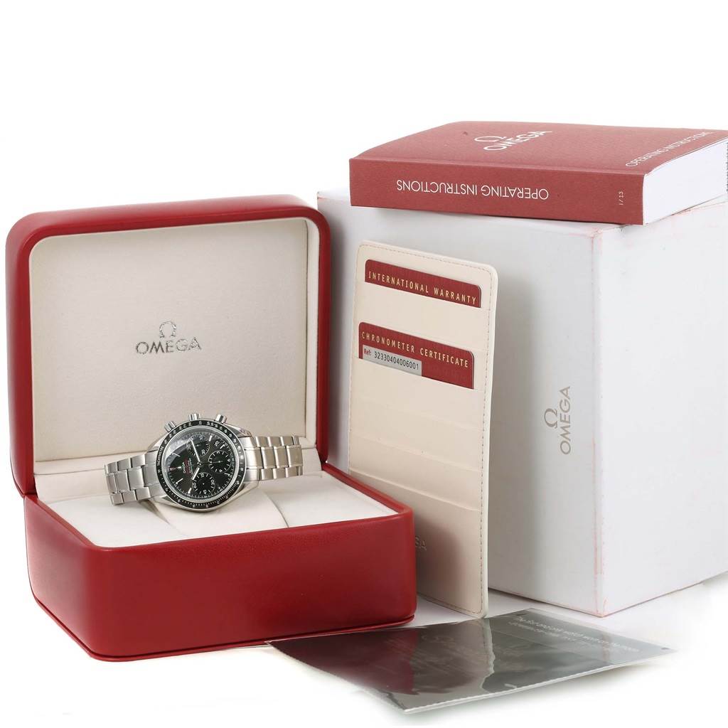 This image shows the Omega Speedmaster 323.30.40.40.06.001 Men
s Stainless Steel Grey Dial 323.30.40.40.06.001 Men
s Stainless Steel Grey Dial watch at an angle in its open box, along with warranty cards and the operating instructions.