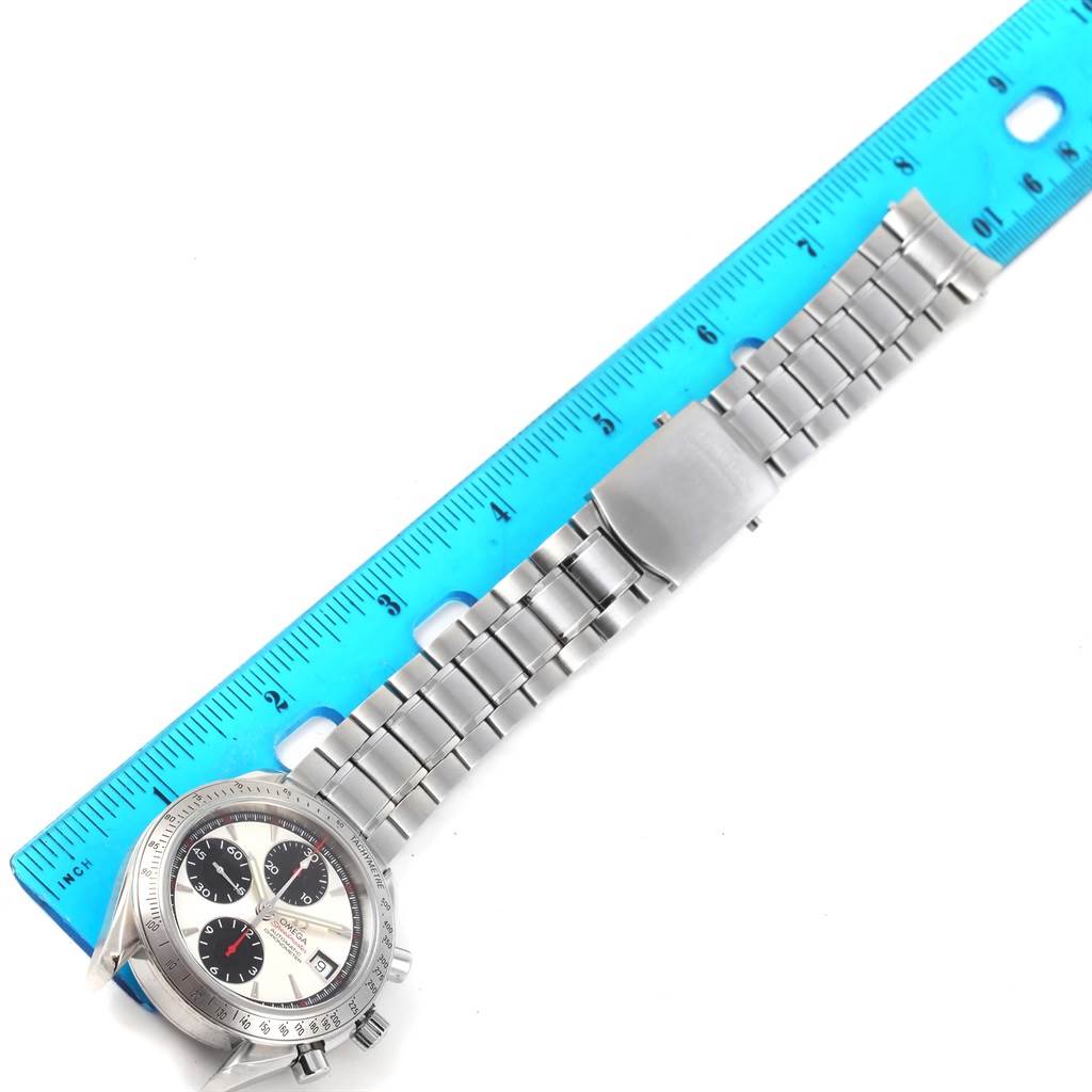 The image shows an Omega Speedmaster 3211.31.00 Men
s Stainless Steel Silver Dial 3211.31.00 Men
s Stainless Steel Silver Dial watch laid flat with a ruler, displaying the face and metal band from an angled top-down view.