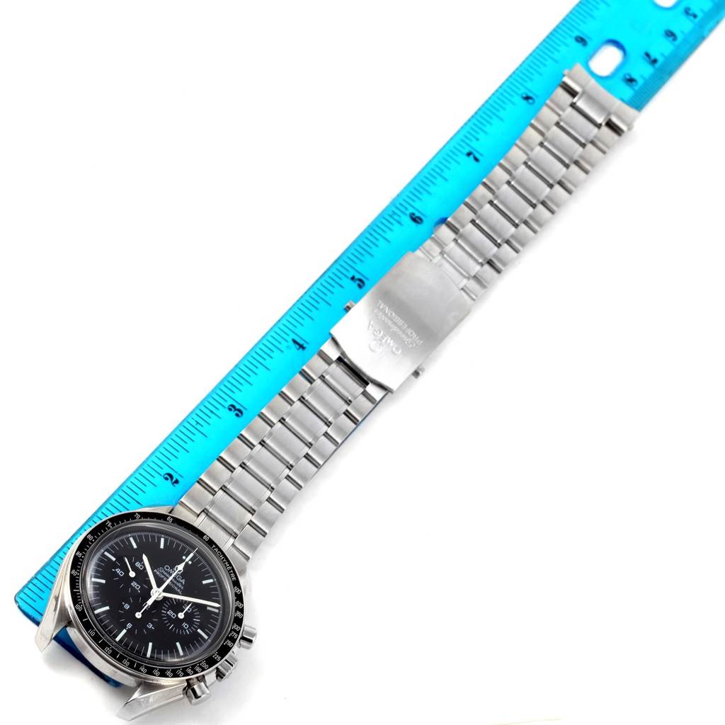 The Omega Speedmaster 3570.50.00 Men
s Stainless Steel Black Dial 3570.50.00 Men
s Stainless Steel Black Dial watch, shown top-down, features its face, bezel, and full metal bracelet next to a blue ruler.