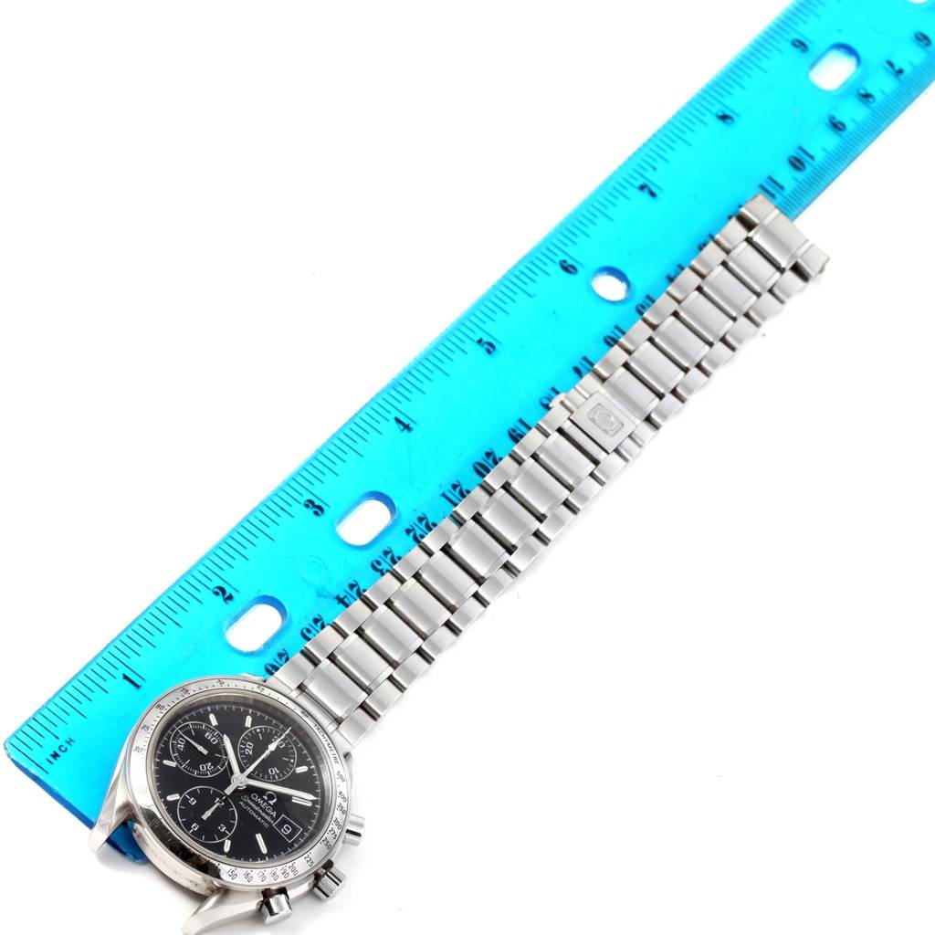 The image shows an Omega Speedmaster 3513.50.00 Men
s Stainless Steel Black Dial 3513.50.00 Men
s Stainless Steel Black Dial watch laid flat, with its face and metal bracelet partially measured by a blue ruler.