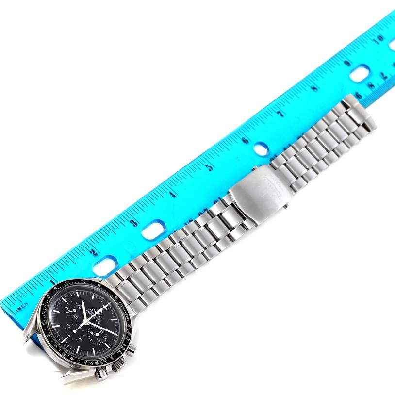 The image shows an Omega Speedmaster 3570.50.00 Men
s Stainless Steel Black Dial 3570.50.00 Men
s Stainless Steel Black Dial watch placed next to a ruler, highlighting the face and full length of its metal bracelet.
