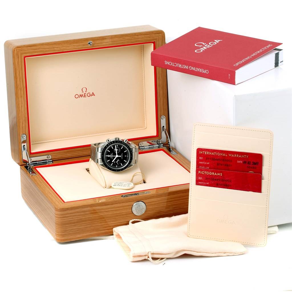 The image shows an Omega Speedmaster 311.30.44.51.01.002 Men
s Stainless Steel Black Dial 311.30.44.51.01.002 Men
s Stainless Steel Black Dial watch in an open wooden box, with warranty cards, a pouch, and an instruction manual.