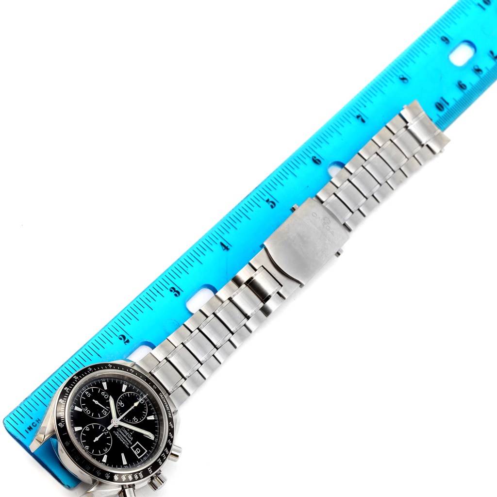 The Omega Speedmaster 3210.50.00 Men
s Stainless Steel Black Dial 3210.50.00 Men
s Stainless Steel Black Dial watch is shown from a top-down angle, displaying its face and metal bracelet alongside a blue ruler for scale.