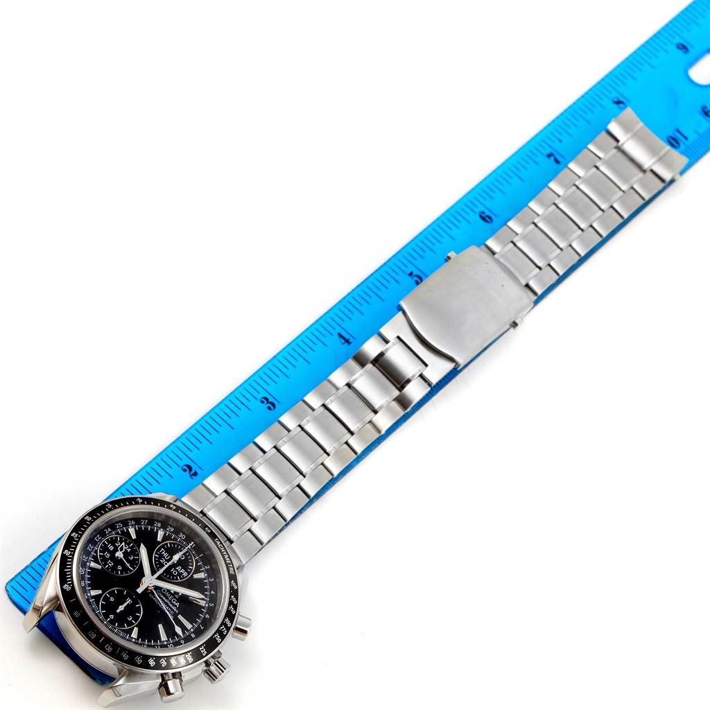 The image shows an Omega Speedmaster 3220.50.00 Men
s Stainless Steel Black Dial 3220.50.00 Men
s Stainless Steel Black Dial watch laid flat next to a blue ruler, displaying its face and metal bracelet from above.