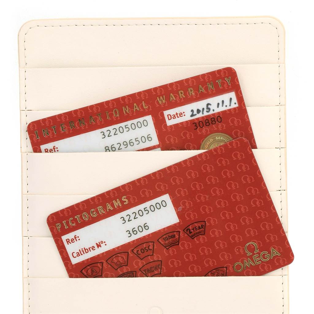 The image shows the warranty and pictograms cards for an Omega Speedmaster 3220.50.00 Men
s Stainless Steel Black Dial 3220.50.00 Men
s Stainless Steel Black Dial watch, placed in a beige card holder.