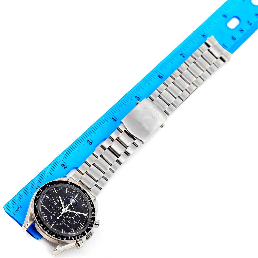 The image shows an Omega Speedmaster 3576.50.00 Men
s Stainless Steel Black Dial 3576.50.00 Men
s Stainless Steel Black Dial watch laid flat next to a ruler, focusing on the watch face and metal bracelet.