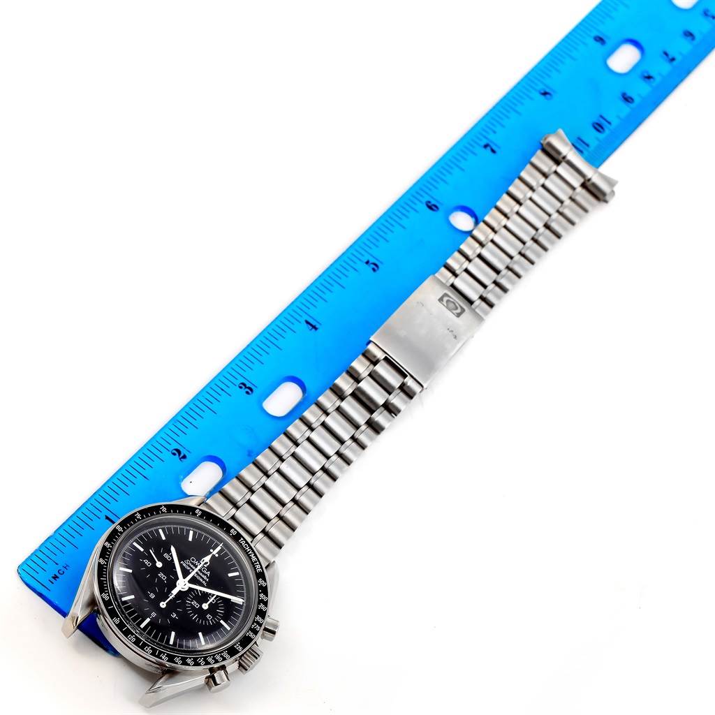 The Omega Speedmaster 3573.50.00 Men
s Stainless Steel Black Dial 3573.50.00 Men
s Stainless Steel Black Dial watch is shown flat, displaying the dial, bezel, and metal bracelet alongside a blue ruler for scale.