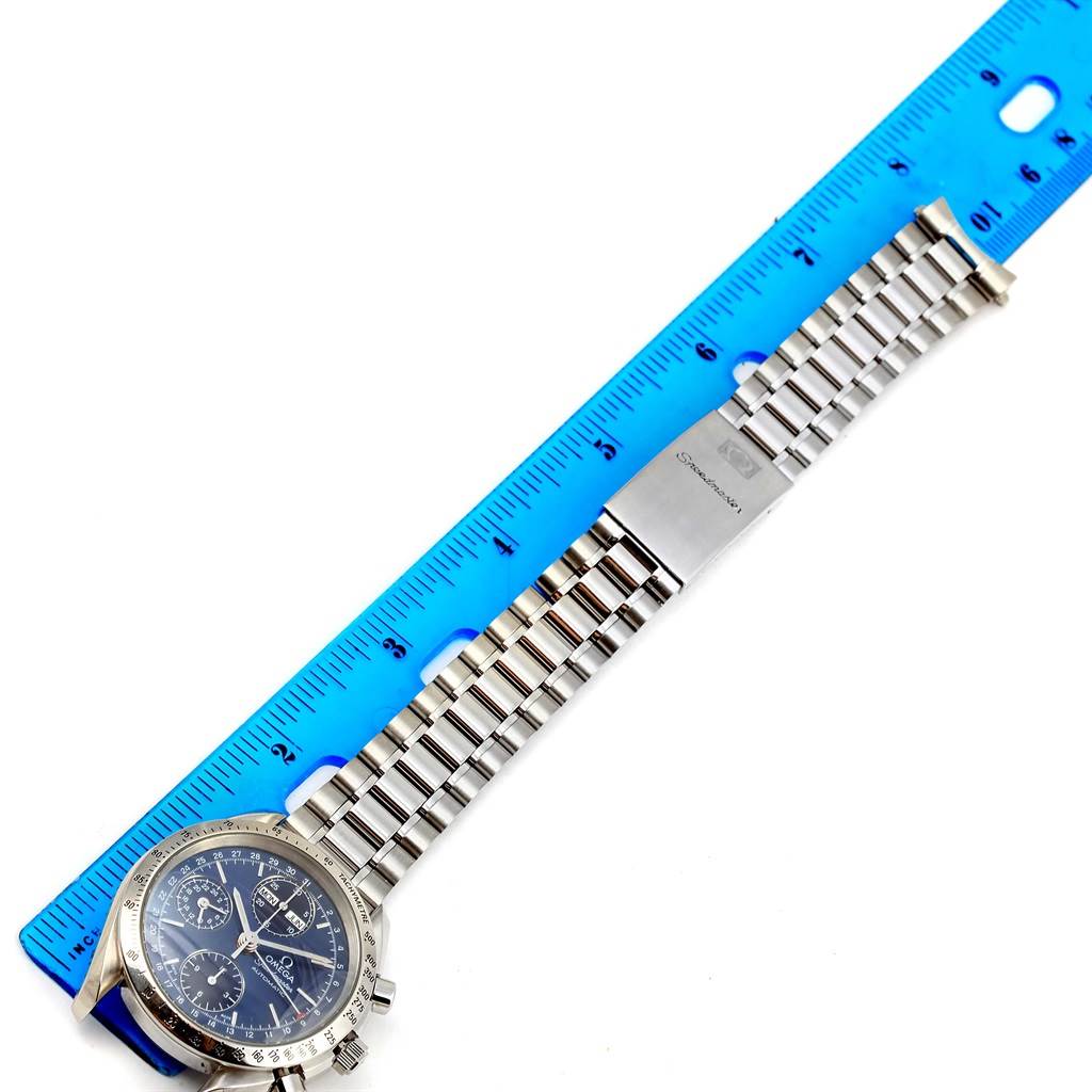 The image shows an Omega Speedmaster 3521.80.00 Men
s Stainless Steel Blue Dial 3521.80.00 Men
s Stainless Steel Blue Dial watch laid flat with its stainless steel bracelet, alongside a blue ruler for scale.