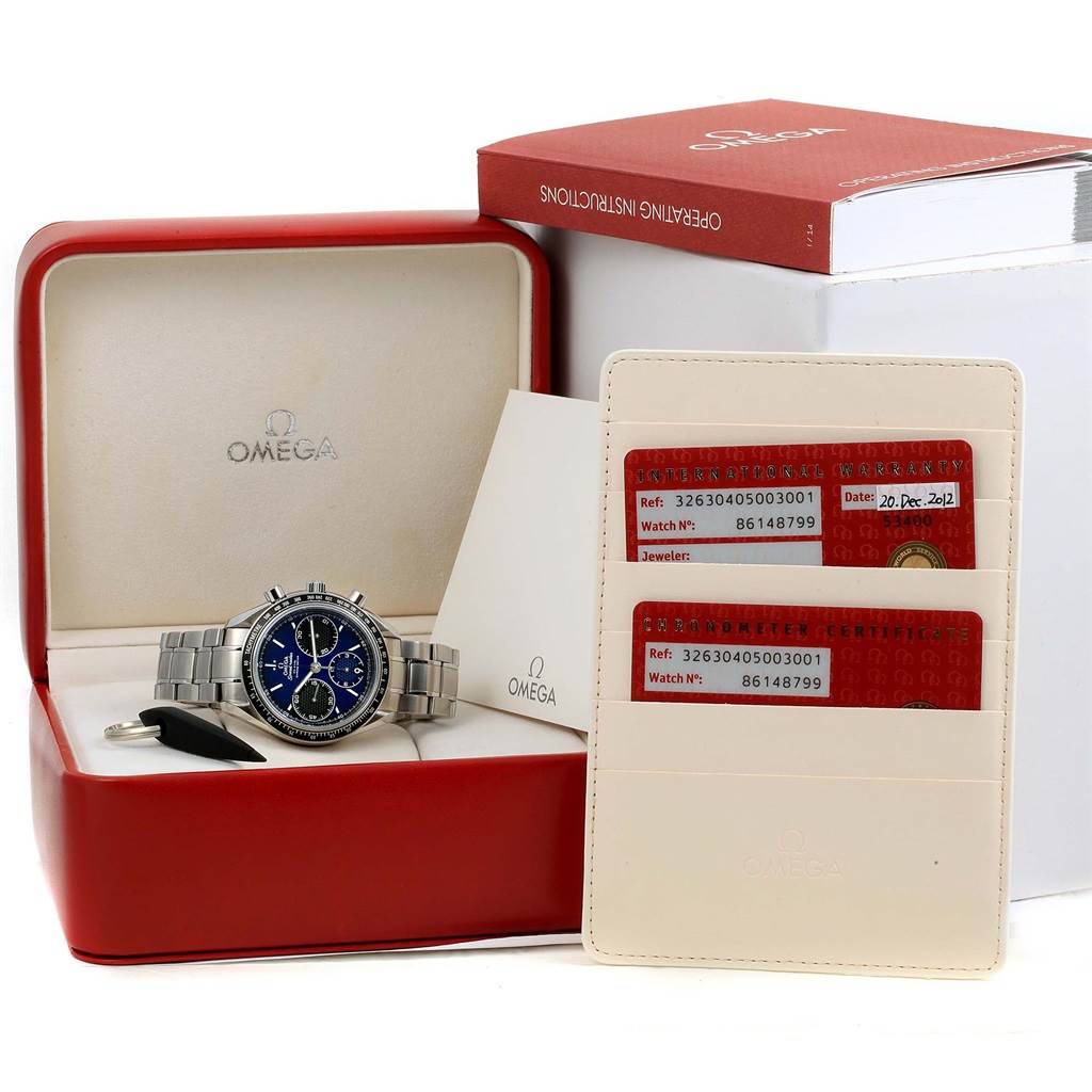 The image shows an Omega Speedmaster 326.30.40.50.03.001 Men
s Stainless Steel Blue Dial 326.30.40.50.03.001 Men
s Stainless Steel Blue Dial watch in its box, along with warranty cards and an instruction manual.