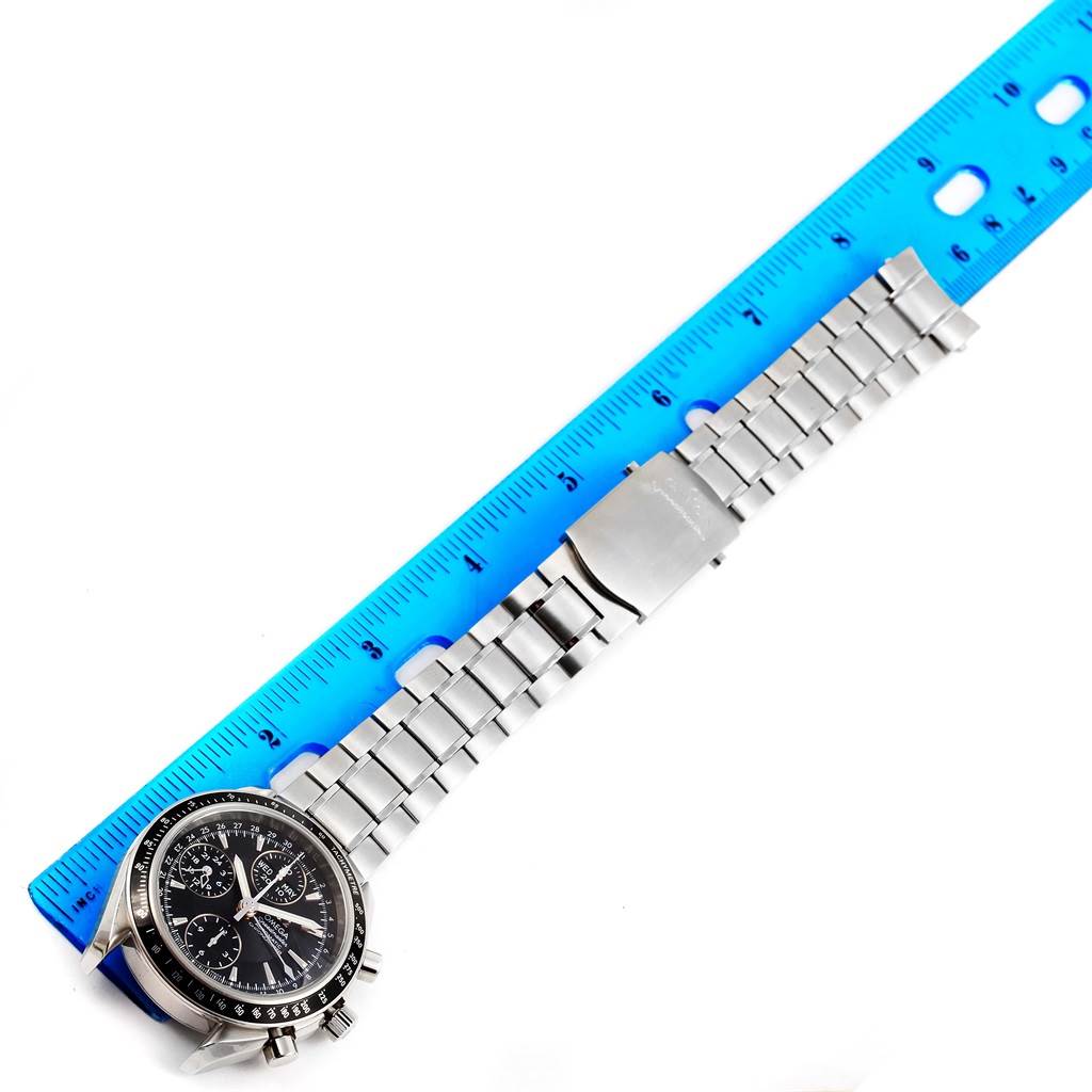 The Omega Speedmaster 3220.50.00 Men
s Stainless Steel Black Dial 3220.50.00 Men
s Stainless Steel Black Dial watch is shown from a top-down angle, displaying the face and metal bracelet against a blue ruler backdrop.