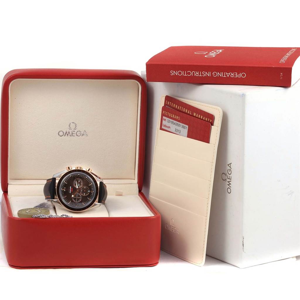 The image shows an Omega Speedmaster 321.93.42.50.13.001 Men
s Steel and Gold (two tone) Brown Dial 321.93.42.50.13.001 Men
s Steel and Gold (two tone) Brown Dial watch in its box, accompanied by an international warranty card and an operating instructions booklet.