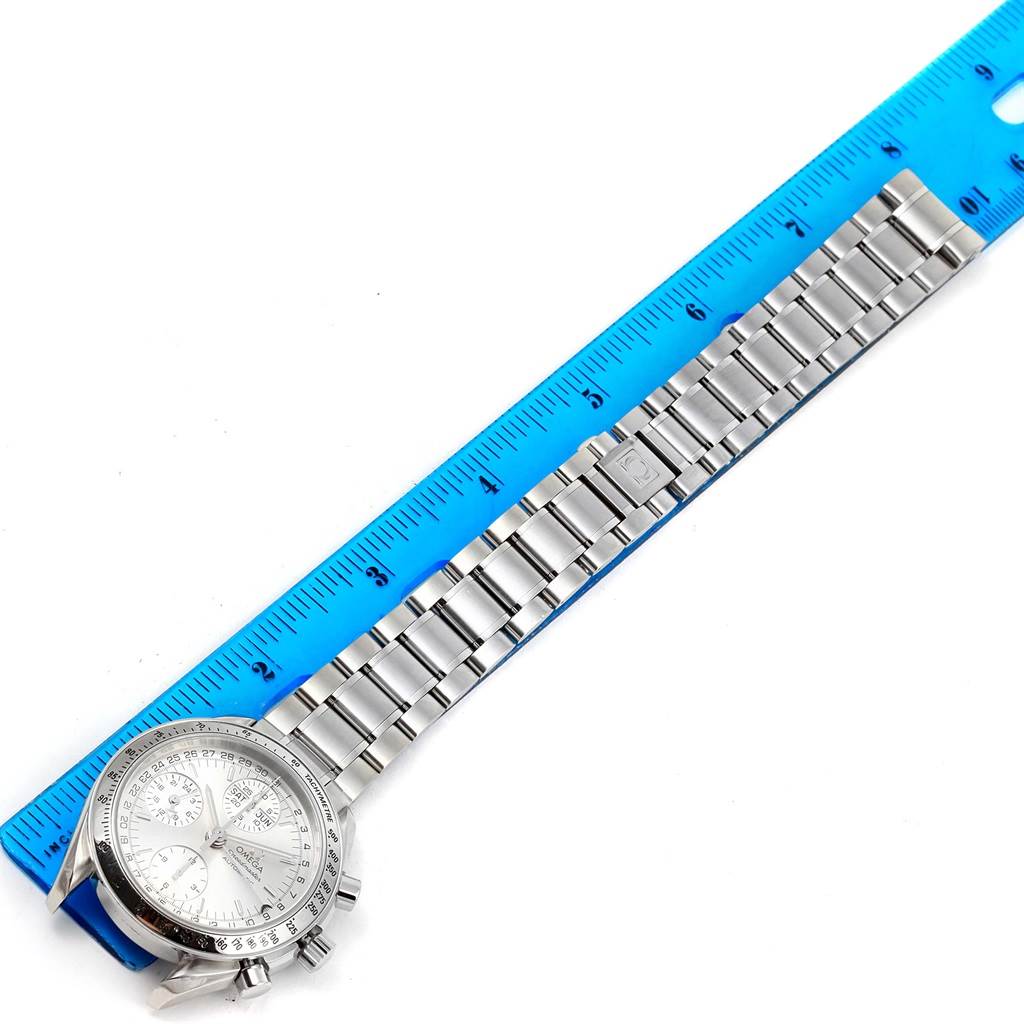 The image shows an Omega Speedmaster 3523.30.00 Men
s Stainless Steel Silver Dial 3523.30.00 Men
s Stainless Steel Silver Dial watch placed along a blue ruler, highlighting the face and stainless steel bracelet.