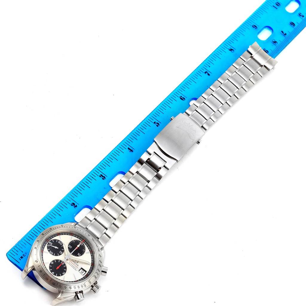 The image shows the Omega Speedmaster 3211.31.00 Men
s Stainless Steel Silver Dial 3211.31.00 Men
s Stainless Steel Silver Dial watch laid flat next to a blue ruler, displaying the face and metal bracelet.