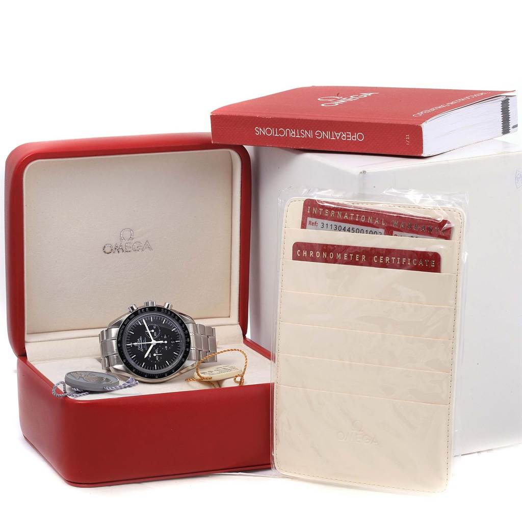 The image shows an Omega Speedmaster 311.30.44.50.01.002 Men
s Stainless Steel Black Dial 311.30.44.50.01.002 Men
s Stainless Steel Black Dial watch in its case, along with an operating manual, warranty card, and chronometer certificate.