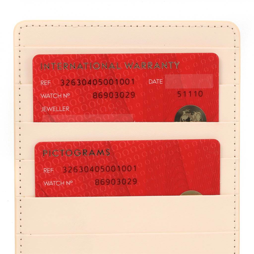 The image shows the International Warranty and Pictograms cards for an Omega Speedmaster 326.30.40.50.01.001 Men
s Stainless Steel Black Dial 326.30.40.50.01.001 Men
s Stainless Steel Black Dial, partially visible inside a cream holder.