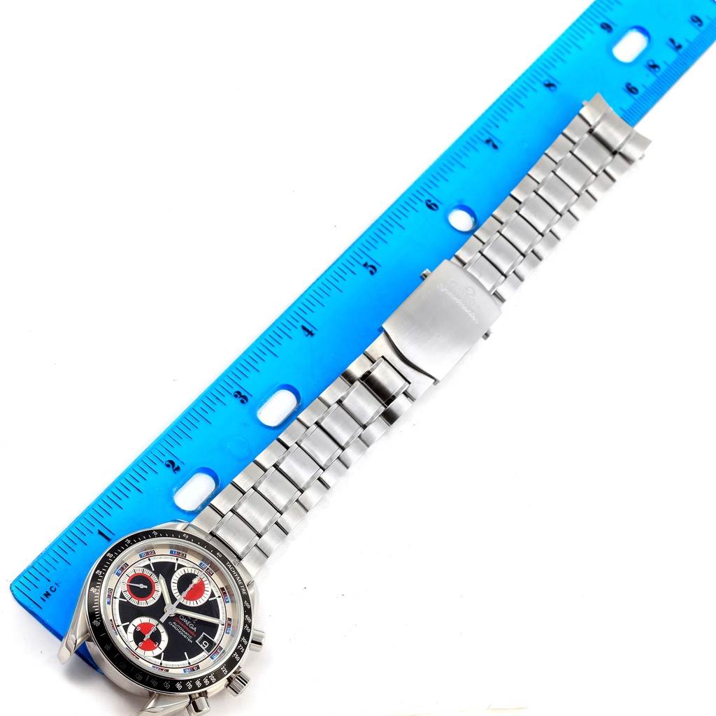 The image shows the Omega Speedmaster 3210.52.00 Men
s Stainless Steel Black Dial 3210.52.00 Men
s Stainless Steel Black Dial watch face and metal bracelet alongside a blue ruler for scale, viewed from above.