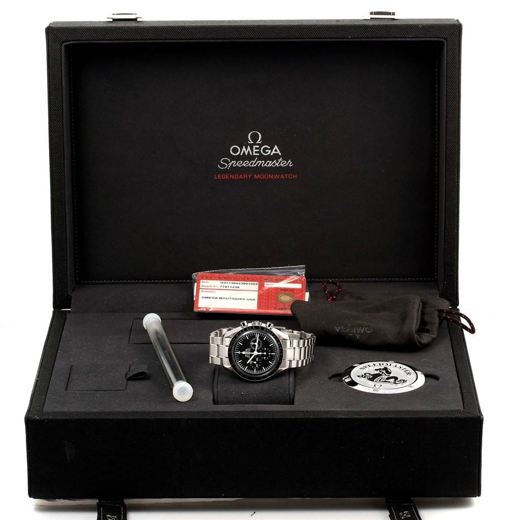 The image shows an Omega Speedmaster 311.30.42.30.01.005 Men
s Stainless Steel Black Dial 311.30.42.30.01.005 Men
s Stainless Steel Black Dial watch and accessories, including a certificate, case, and additional components, from a top-down angle.