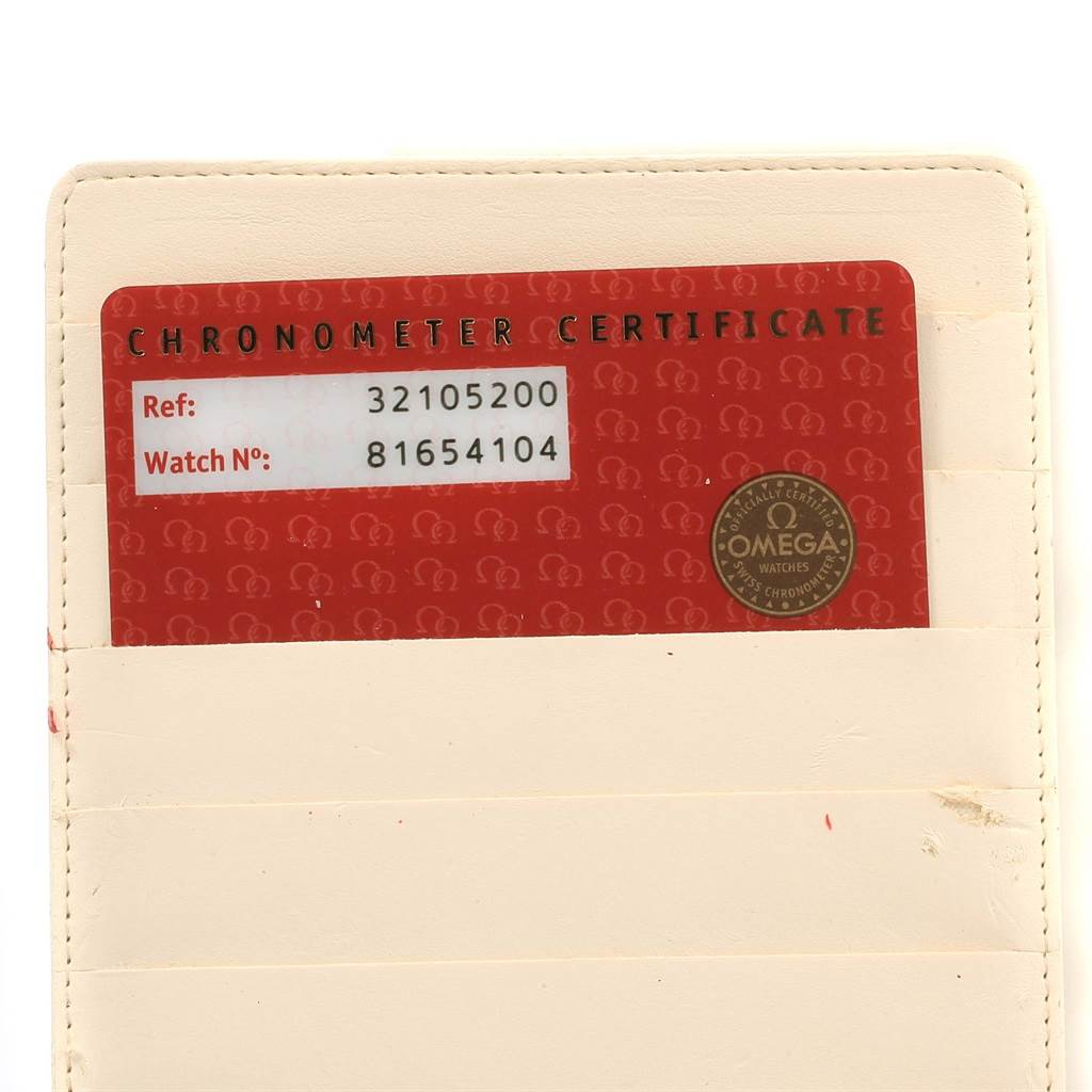 The image shows a red chronometer certificate card for an Omega Speedmaster 3210.52.00 Men
s Stainless Steel Black Dial 3210.52.00 Men
s Stainless Steel Black Dial with reference and watch numbers, placed in a beige holder.