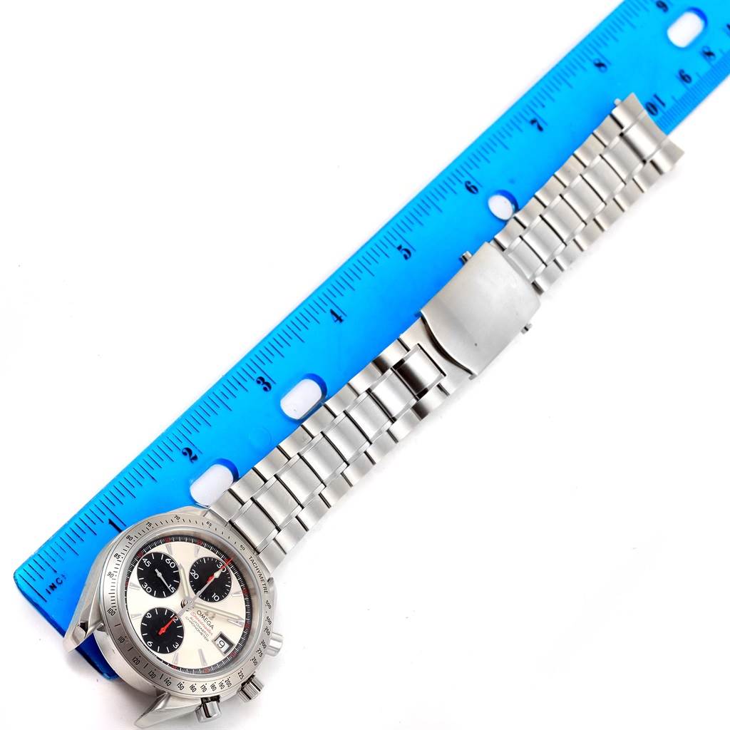 This image shows an Omega Speedmaster 3211.31.00 Men
s Stainless Steel Silver Dial 3211.31.00 Men
s Stainless Steel Silver Dial watch, laying flat with its face, bracelet, and clasp visible, alongside a blue ruler for measurement.