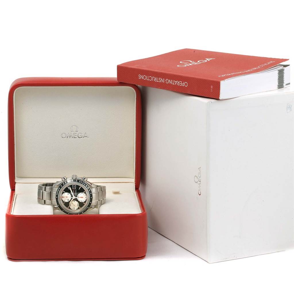 The image shows an Omega Speedmaster 3210.51.00 Men
s Stainless Steel Black Dial 3210.51.00 Men
s Stainless Steel Black Dial watch in an open red case with a white exterior box and a red operating instructions booklet beside it.