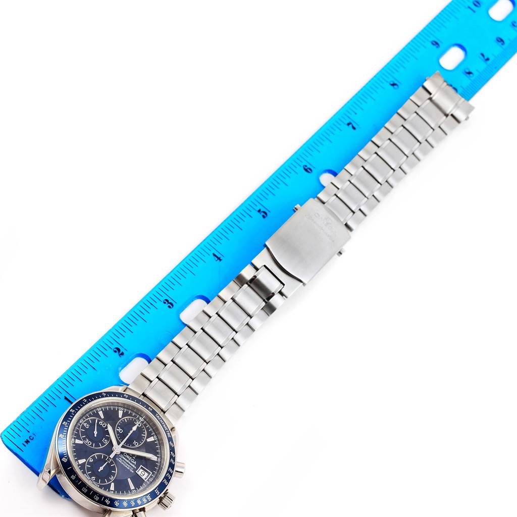 The Omega Speedmaster 3212.80.00 Men
s Stainless Steel Blue Dial 3212.80.00 Men
s Stainless Steel Blue Dial watch is shown from a top-down angle with its full stainless steel bracelet and clasp alongside a blue ruler.