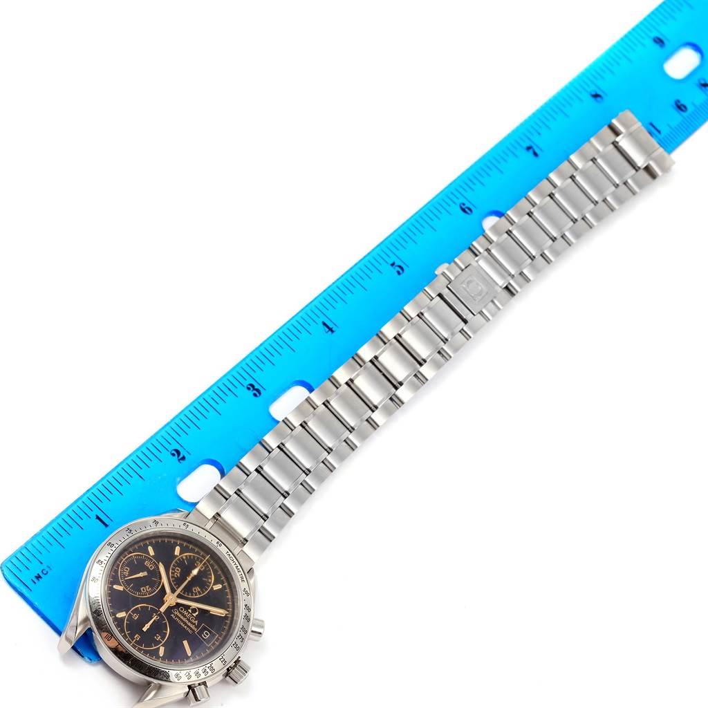 The image shows the Omega Speedmaster 3513.54.00 Men
s Stainless Steel Black Dial 3513.54.00 Men
s Stainless Steel Black Dial watch from an overhead angle, highlighting the watch face and the metal bracelet alongside a blue ruler.