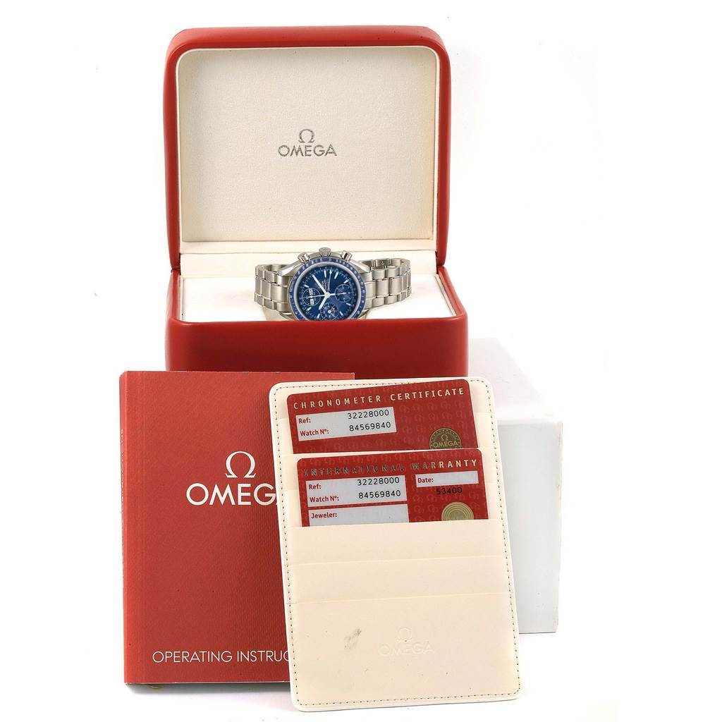 The image shows an Omega Speedmaster 3222.80.00 Men
s Stainless Steel Blue Dial 3222.80.00 Men
s Stainless Steel Blue Dial watch in its open red box, with warranty cards, a chronometer certificate, and an operating manual.
