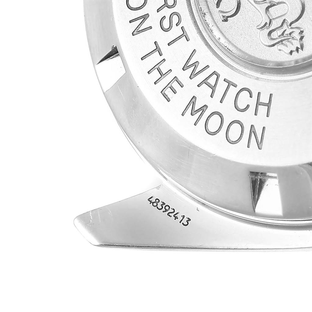 The image shows the back of an Omega Speedmaster 3570.50.00 Men
s Stainless Steel Black Dial 3570.50.00 Men
s Stainless Steel Black Dial watch with the engraved text "FIRST WATCH ON THE MOON" and a partial serial number.