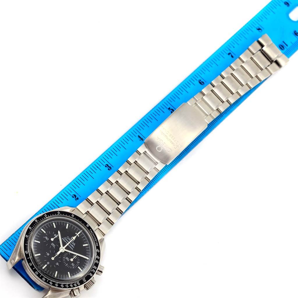 The image shows an overhead view of an Omega Speedmaster 3572.50.00 Men
s Stainless Steel Black Dial 3572.50.00 Men
s Stainless Steel Black Dial watch, displaying its face, bracelet, and clasp next to a ruler for scale.