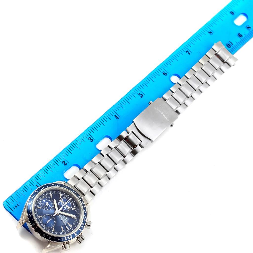The image shows the Omega Speedmaster 3222.80.00 Men
s Stainless Steel Blue Dial 3222.80.00 Men
s Stainless Steel Blue Dial watch laid flat next to a blue ruler for scale, showcasing the dial and metal bracelet.
