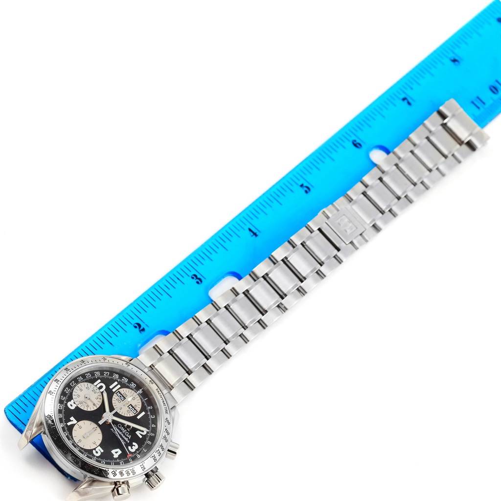 The image shows an Omega Speedmaster 3523.51.00 Men
s Stainless Steel Black Dial 3523.51.00 Men
s Stainless Steel Black Dial watch with a metal bracelet beside a blue ruler, captured from a top-down angle.