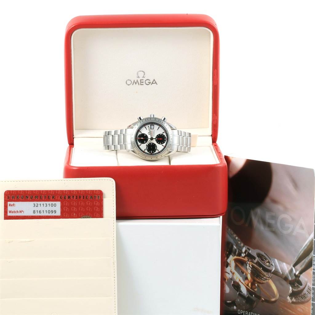 The image shows an Omega Speedmaster 3211.31.00 Men
s Stainless Steel Silver Dial 3211.31.00 Men
s Stainless Steel Silver Dial watch in a red and white box, alongside a cardholder and a manual.
