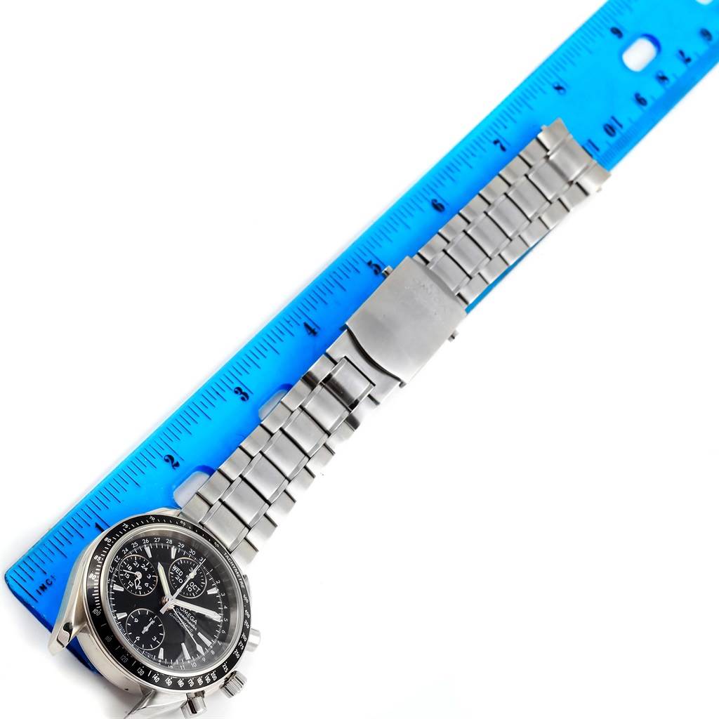 The image shows an Omega Speedmaster 3220.50.00 Men
s Stainless Steel Black Dial 3220.50.00 Men
s Stainless Steel Black Dial watch with a metal bracelet next to a blue ruler, taken from a slightly tilted overhead angle.