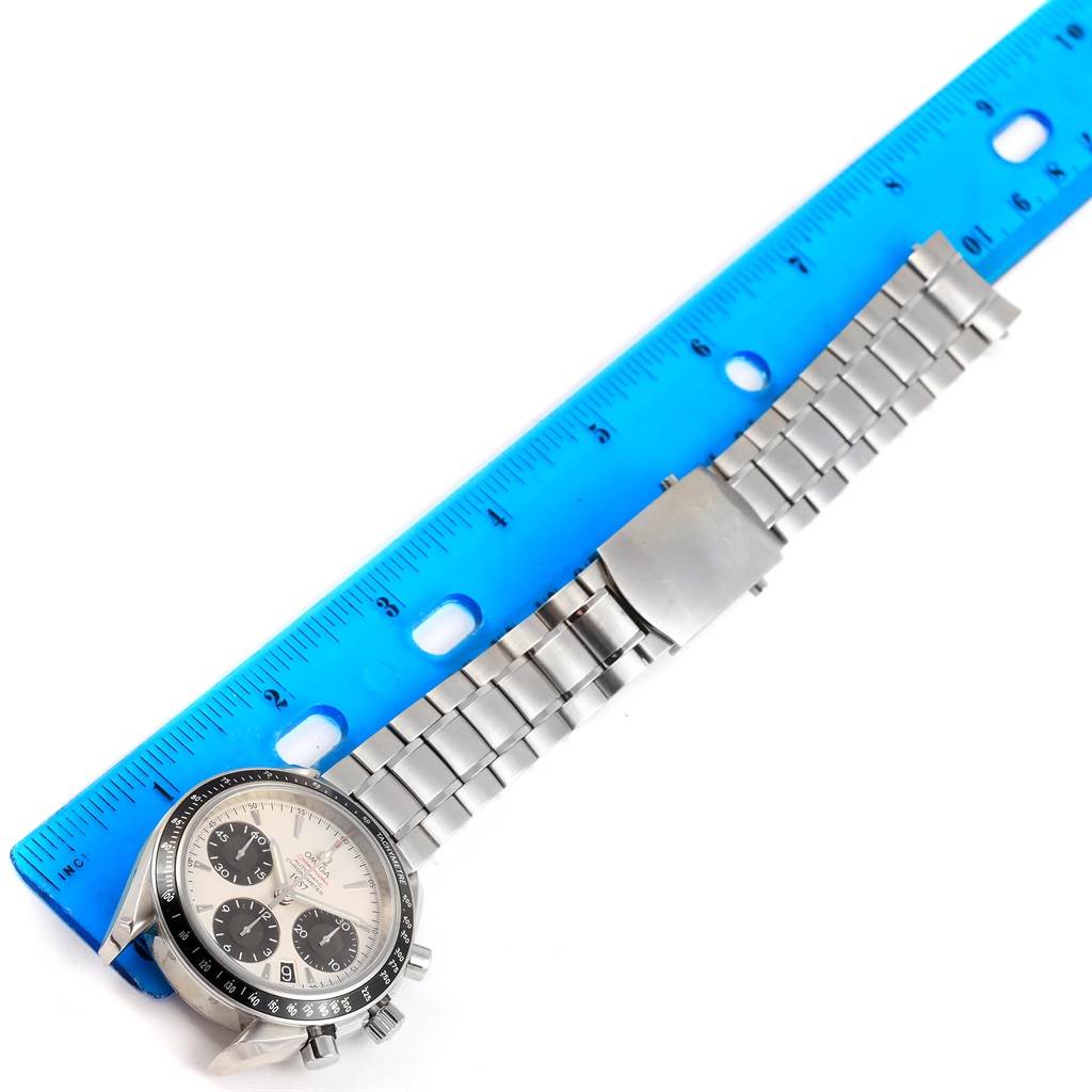 This image shows an Omega Speedmaster 323.30.40.40.02.001 Men's Stainless Steel White Dial 323.30.40.40.02.001 Men's Stainless Steel White Dial watch face, bezel, and bracelet next to a blue ruler for scale.