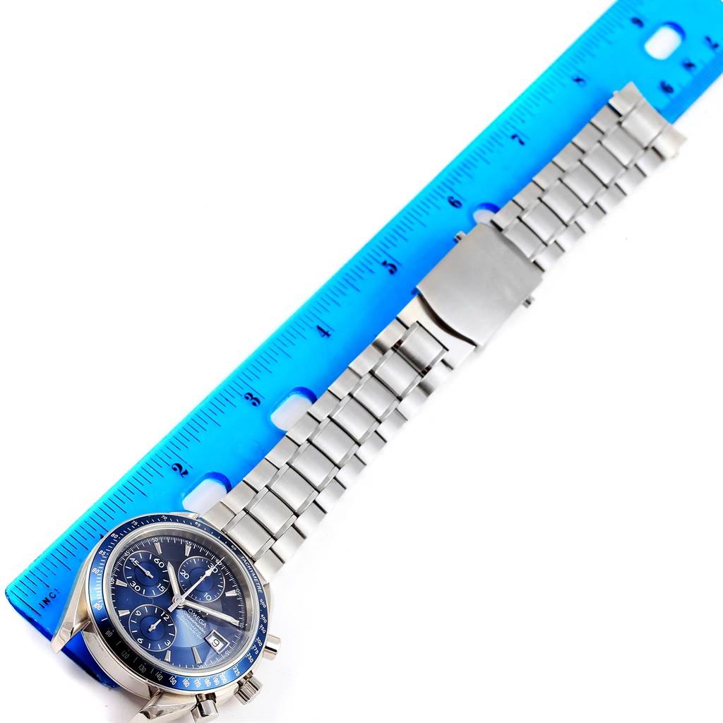 The image shows an Omega Speedmaster 3212.80.00 Men
s Stainless Steel Blue Dial 3212.80.00 Men
s Stainless Steel Blue Dial watch with a metal bracelet and clasp, positioned next to a blue ruler for scale.