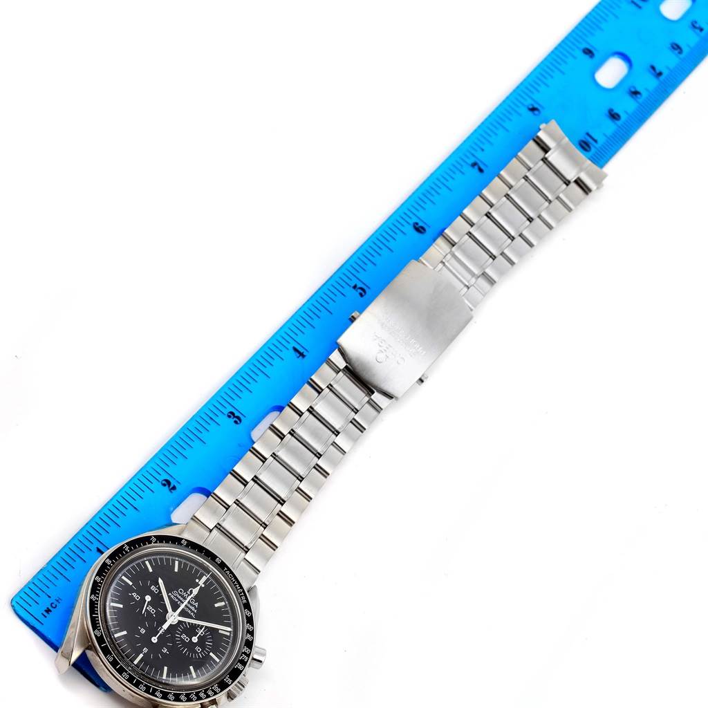 The image shows an Omega Speedmaster 3570.50.00 Men's Stainless Steel Black Dial 3570.50.00 Men's Stainless Steel Black Dial watch laid flat with its metal bracelet extended next to a blue ruler.