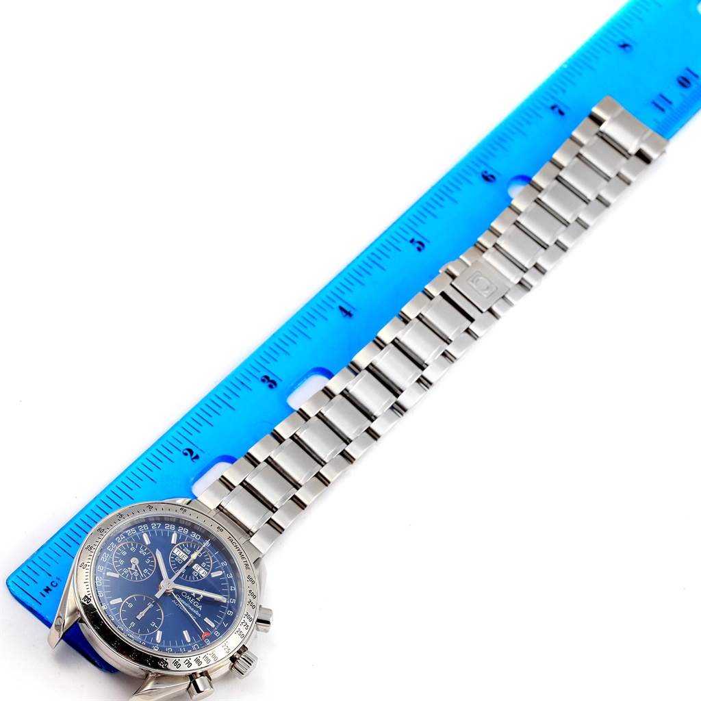 The image shows an Omega Speedmaster 3523.80.00 Men
s Stainless Steel Blue Dial 3523.80.00 Men
s Stainless Steel Blue Dial watch laid next to a blue ruler, highlighting the face, bezel, and metal bracelet.