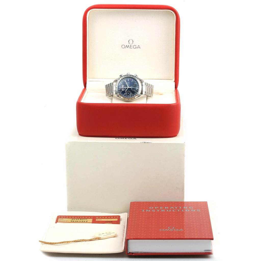 The Omega Speedmaster 3523.80.00 Men's Stainless Steel Blue Dial 3523.80.00 Men's Stainless Steel Blue Dial watch is displayed in an open red case with manuals and a warranty card beside it.
