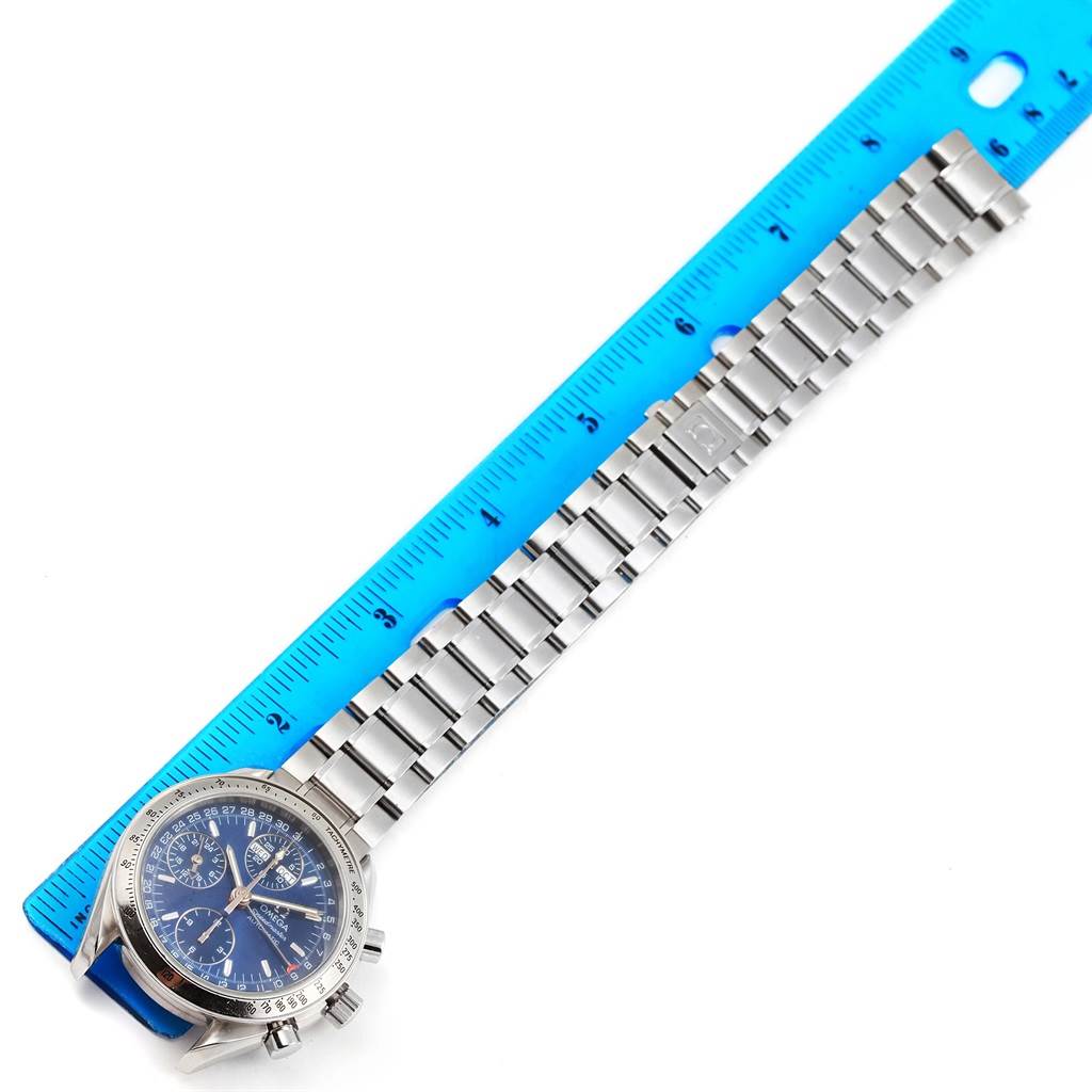 The image shows an Omega Speedmaster 3523.80.00 Men
s Stainless Steel Blue Dial 3523.80.00 Men
s Stainless Steel Blue Dial watch laid flat next to a blue ruler, displaying the face, bezel, and metal bracelet.