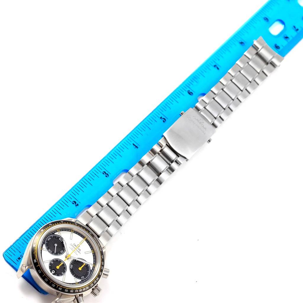 The image displays a top-down view of an Omega Speedmaster 326.30.40.50.04.001 Men
s Stainless Steel White Dial 326.30.40.50.04.001 Men
s Stainless Steel White Dial watch with a metal bracelet and a blue ruler for scale.