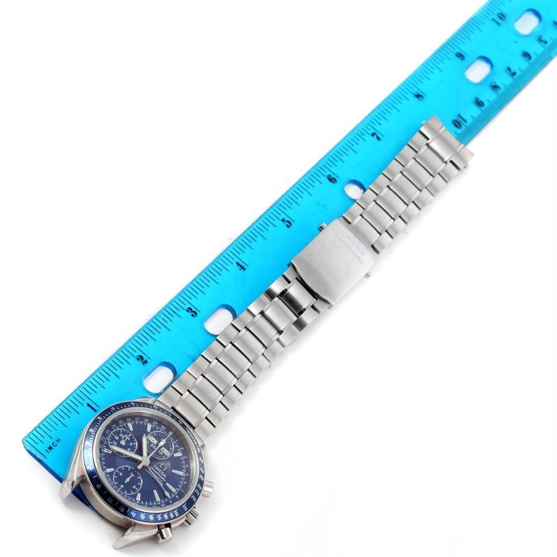 The image shows an Omega Speedmaster 3222.80.00 Men
s Stainless Steel Blue Dial 3222.80.00 Men
s Stainless Steel Blue Dial watch laid flat with its stainless steel band and clasp, alongside a blue ruler for measurement.