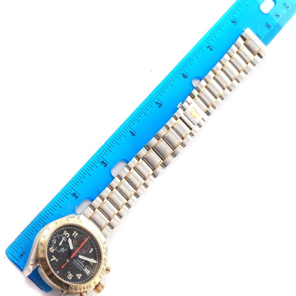 The Omega Speedmaster 3313.53.00 Men's Steel and Gold (two tone) Black Dial 3313.53.00 Men's Steel and Gold (two tone) Black Dial watch is shown from a top-down angle alongside a measuring ruler, focusing on the watch face and band.